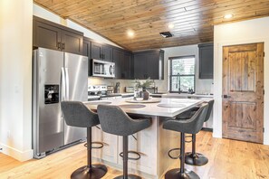 Una cocina moderna con una isla central, electrodomésticos de acero inoxidable y armarios oscuros.
