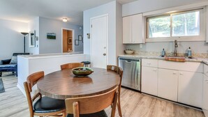 A modern kitchen with white cabinets, a stainless steel dishwasher, and a window above the sink.