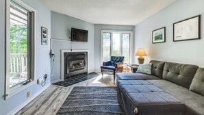 A living room with a fireplace, a sofa, a chair, and a TV mounted on the wall.
