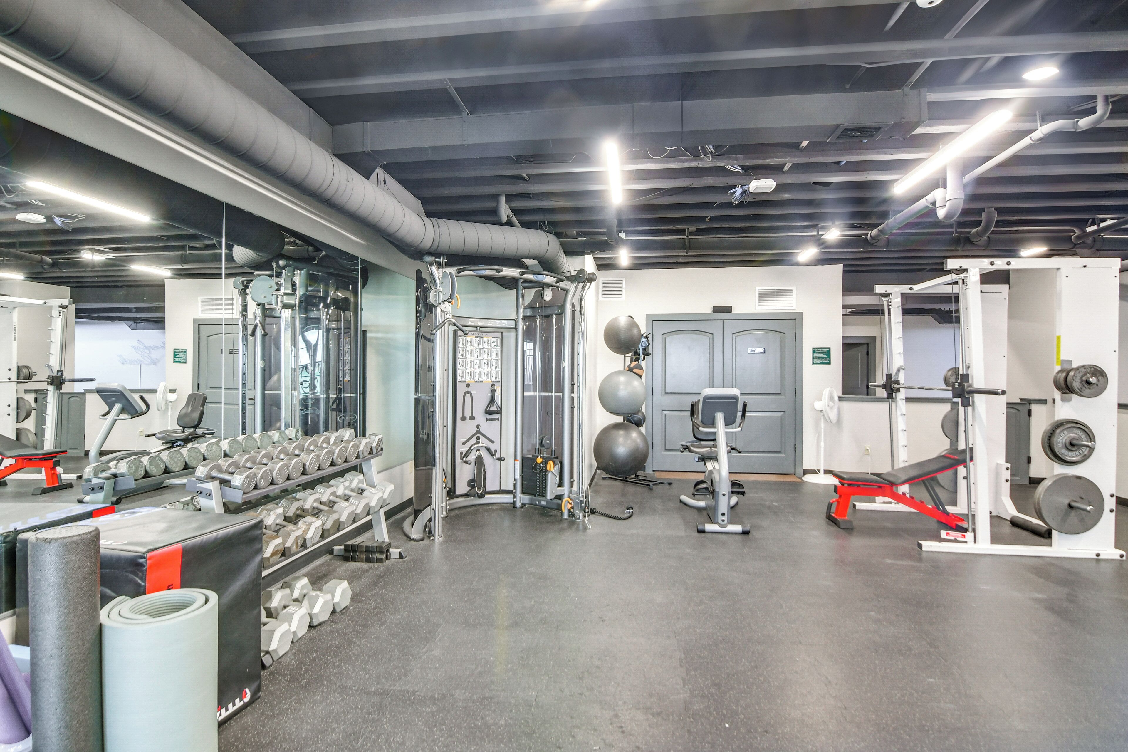A gym with various exercise equipment, including dumbbells, a bench press, and weight machines.