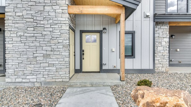 A modern two-story house with a stone facade, a wooden porch, and a concrete pathway leading to the entrance. - Granby Ranch Escape: Shuttle to the Slopes! (Granby)