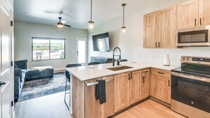 A modern kitchen with wooden cabinets, a stainless steel oven, and pendant lighting. - Granby Ranch Escape: Shuttle to the Slopes! (Granby)