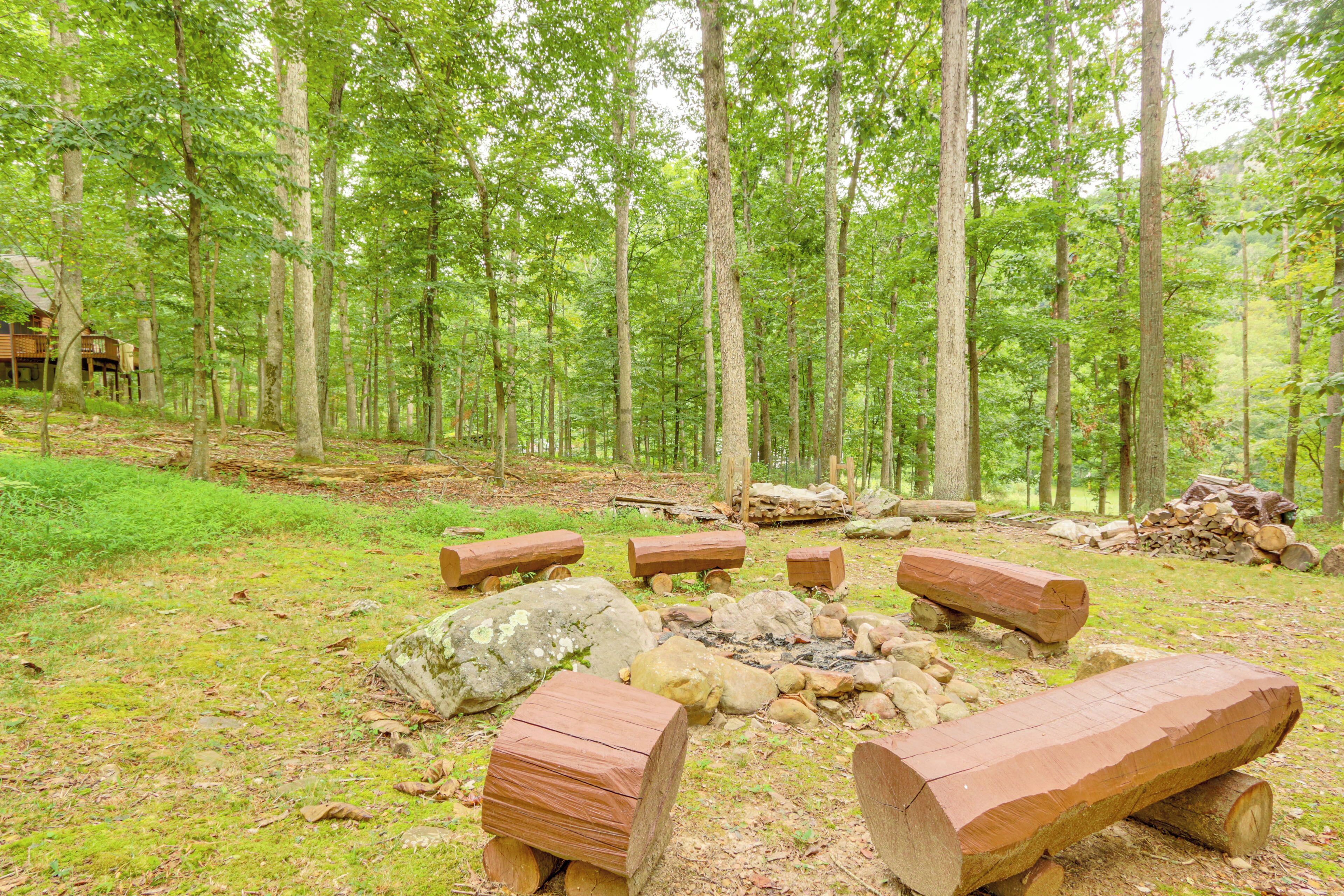 A forest with a cabin and a fire pit area.