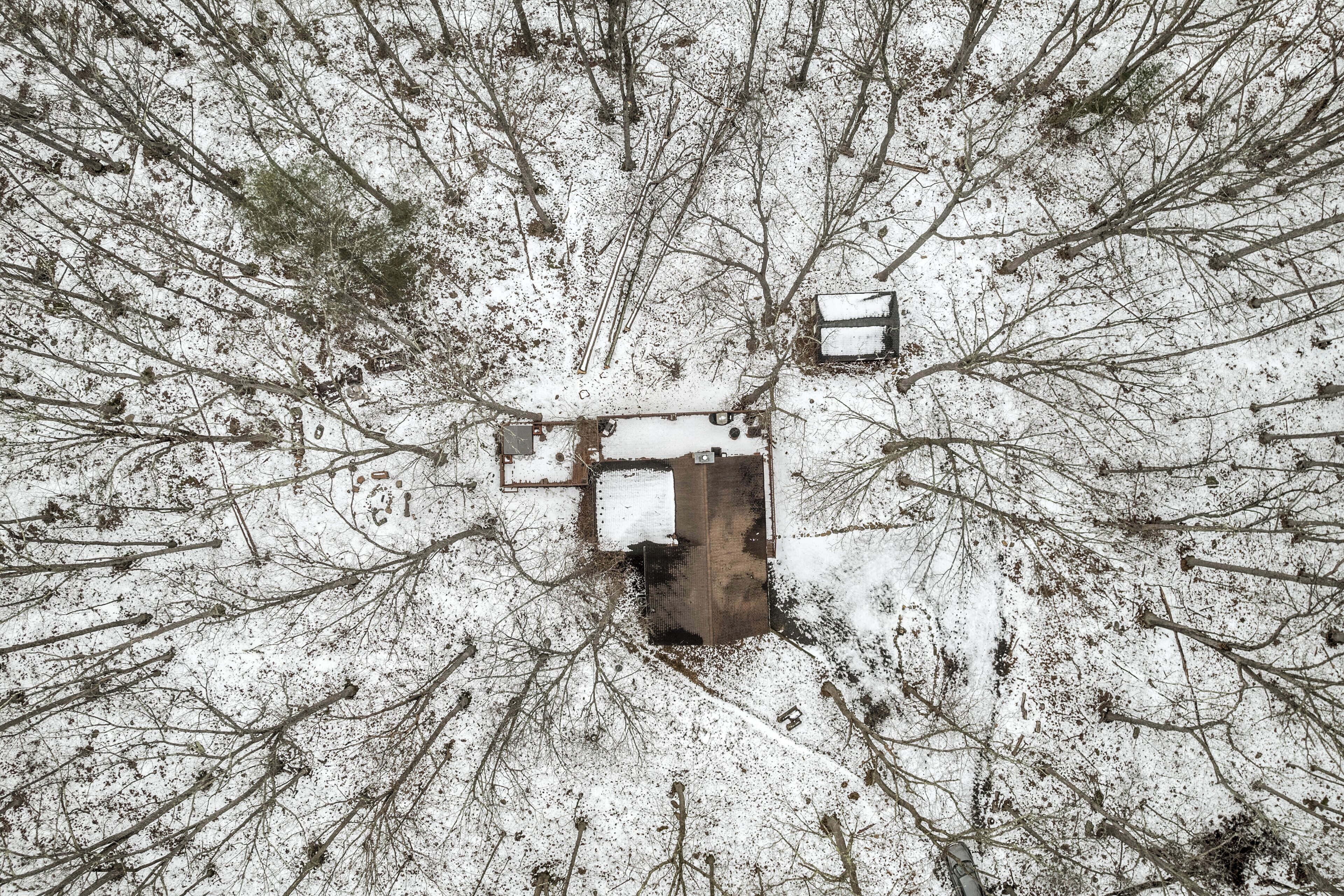 Paisatge cobert de neu amb una estructura al centre i arbres sense fulles al voltant.