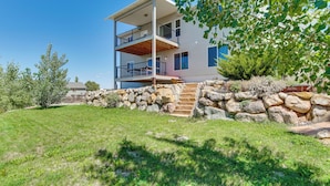 A modern two-story house with a stone staircase leading to a wooden deck. - Panoramic Views: Spacious Home in Cedar City! (Cedar City)