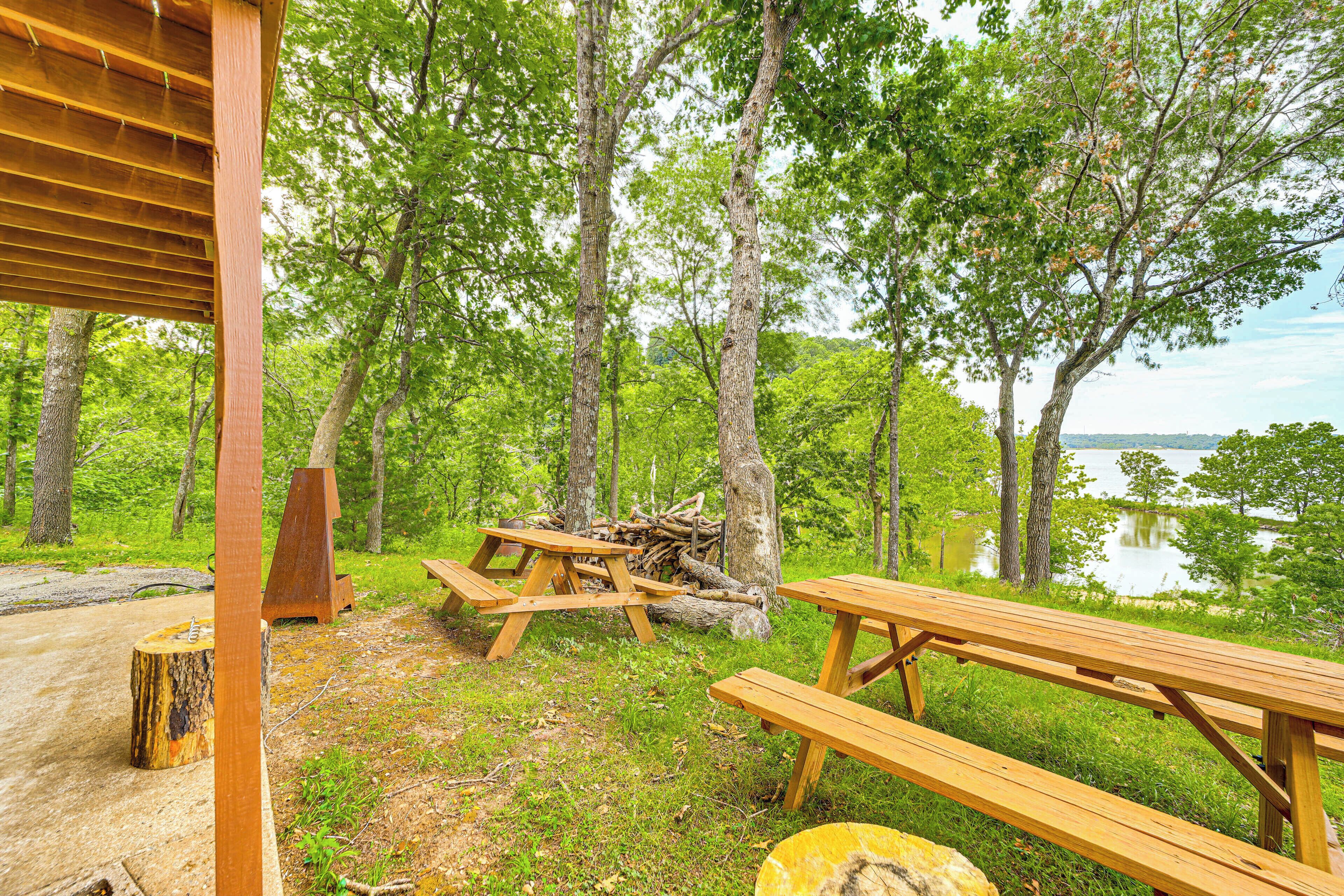 Une table et des bancs en bois, installés dans un espace boisé, offrent une vue sur un lac.