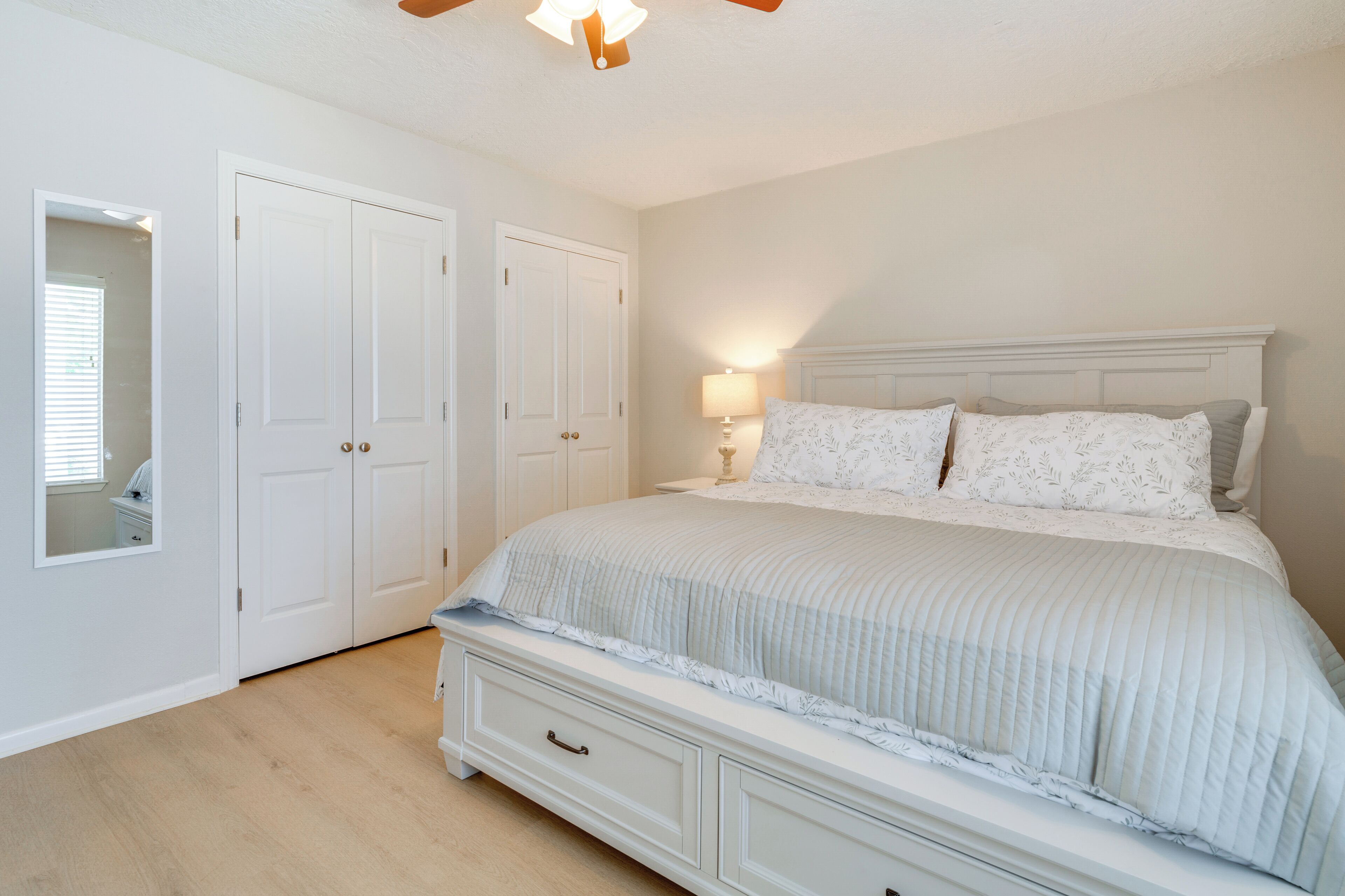 A bedroom with a bed, a nightstand, a lamp, and a wardrobe.