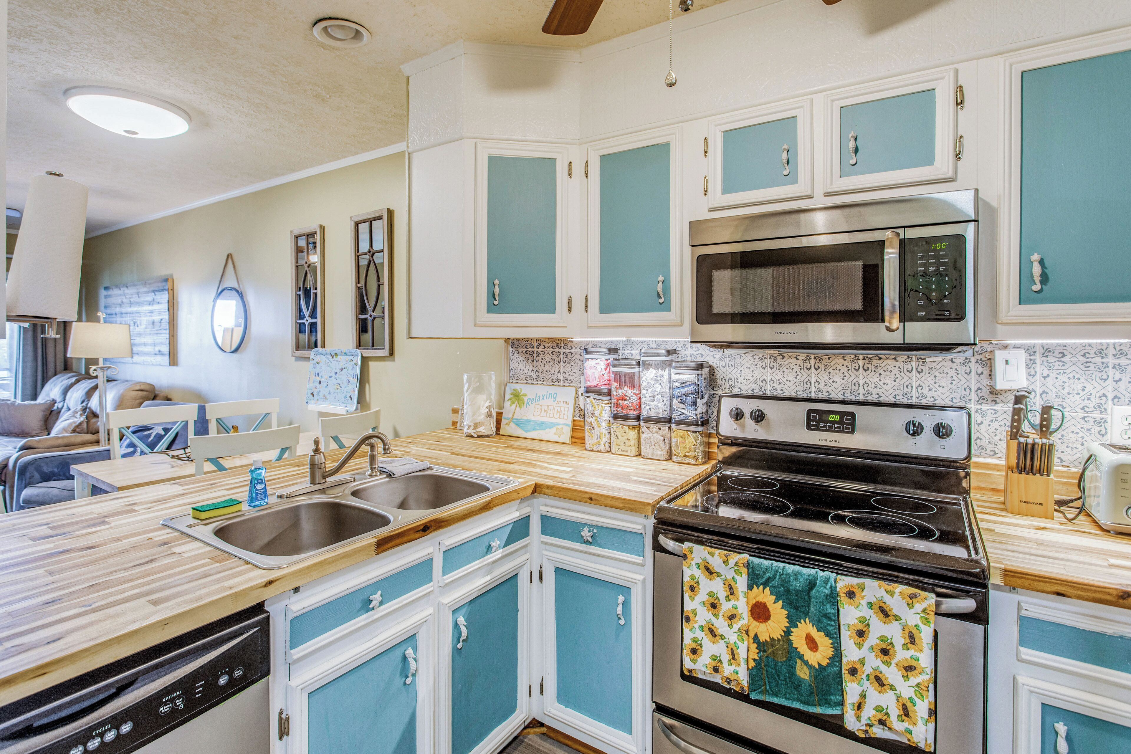 A kitchen with a dishwasher, double sink, microwave, stove, and a refrigerator.