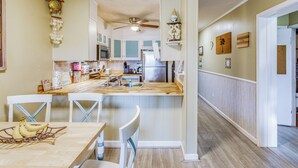 A kitchen with white cabinets, a wooden island, and a dining area with white chairs. - 'shore Drive Serenity' - Steps to Ocean Annies! (Myrtle Beach)