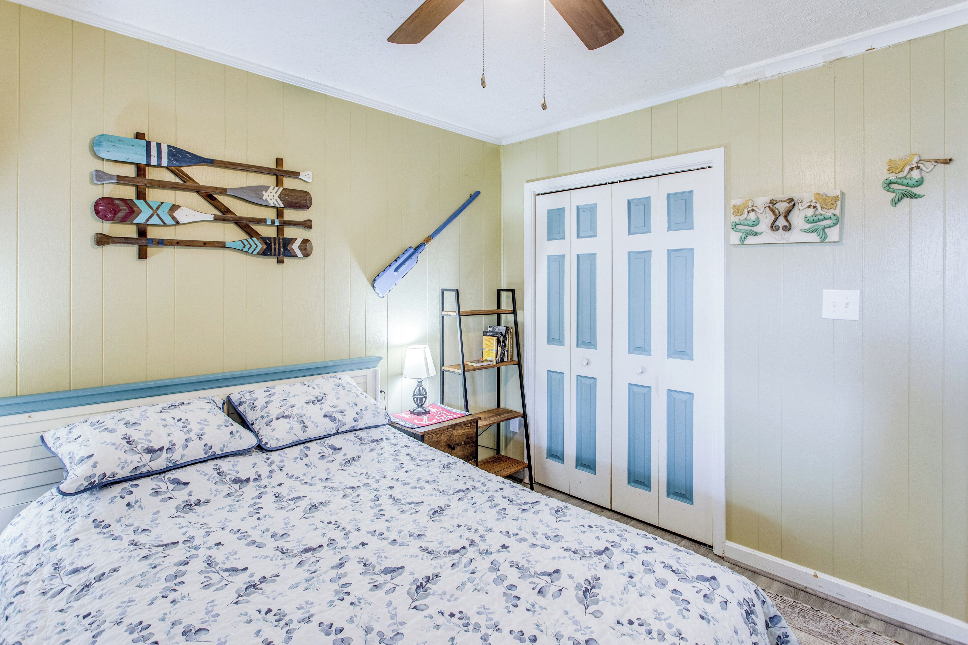Un dormitorio con cama, repisa de madera, puerta y adornos en la pared.