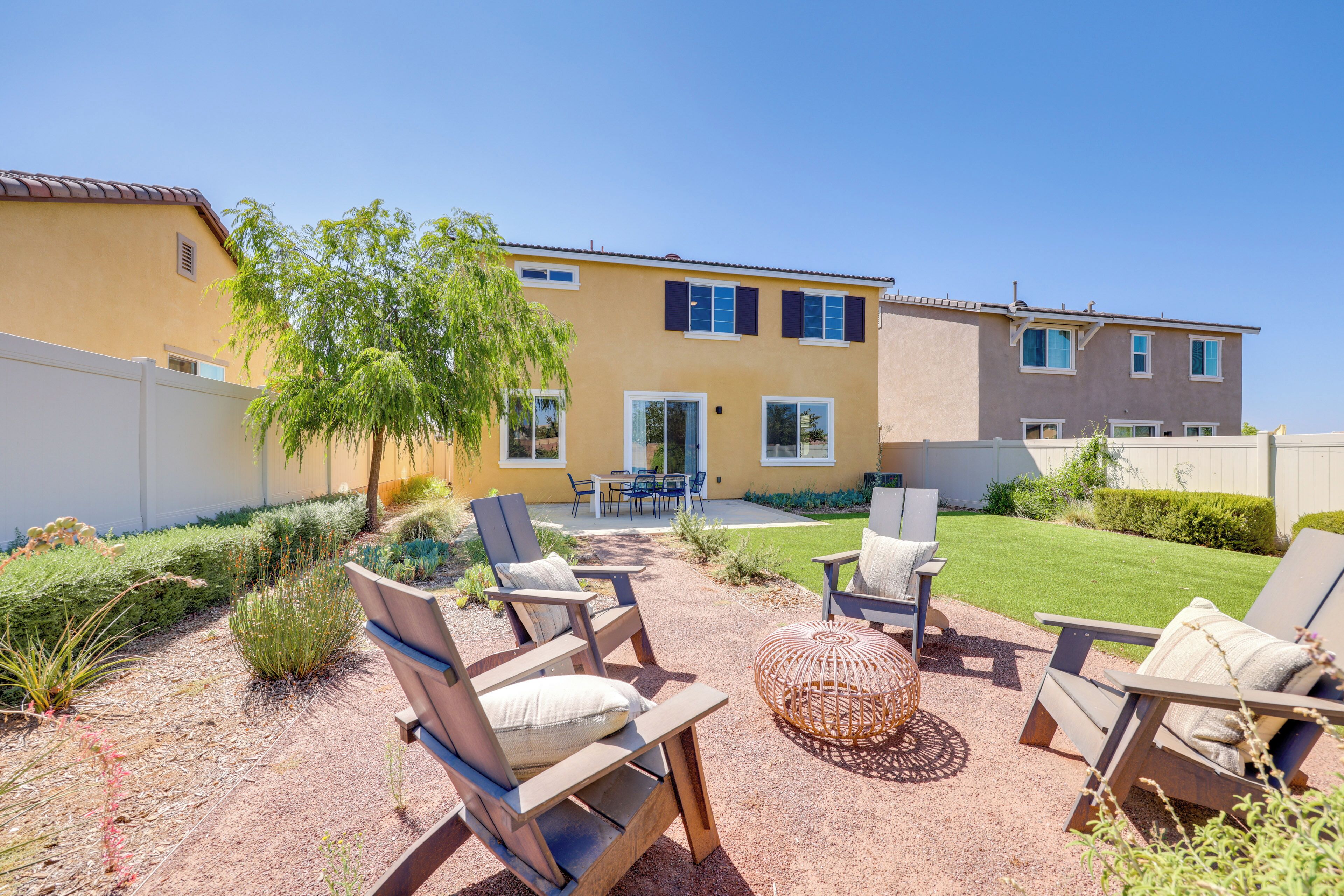 A backyard with outdoor furniture, a dining area, and a building with a yellow exterior.