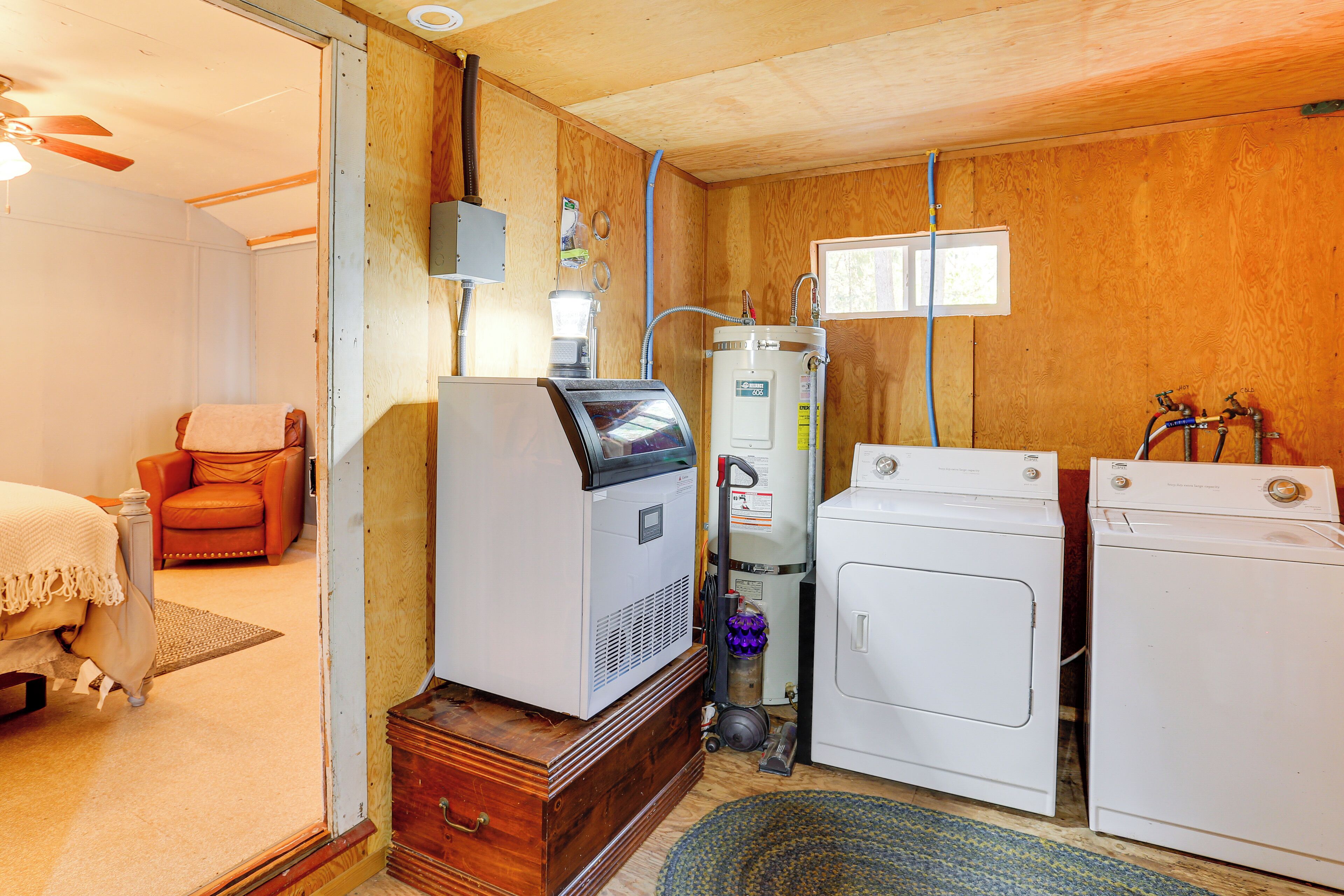 A compact room with a bed, a chair, a heater, a washing machine, and a dryer.