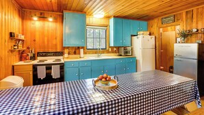 A wooden cabin with a kitchen featuring a stove, sink, and refrigerator.