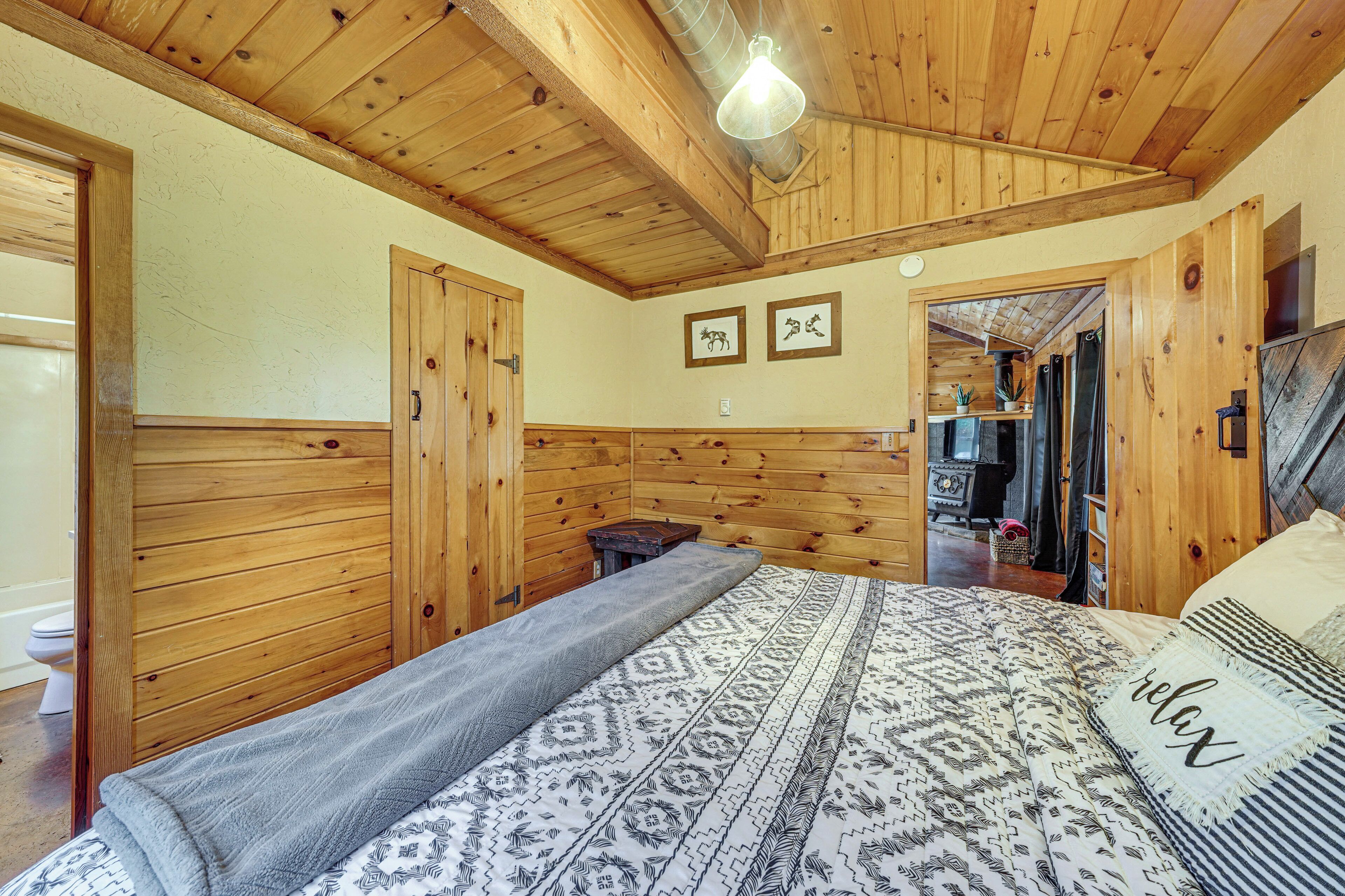 A wooden room with a bed, a wardrobe, and a door leading to another room.