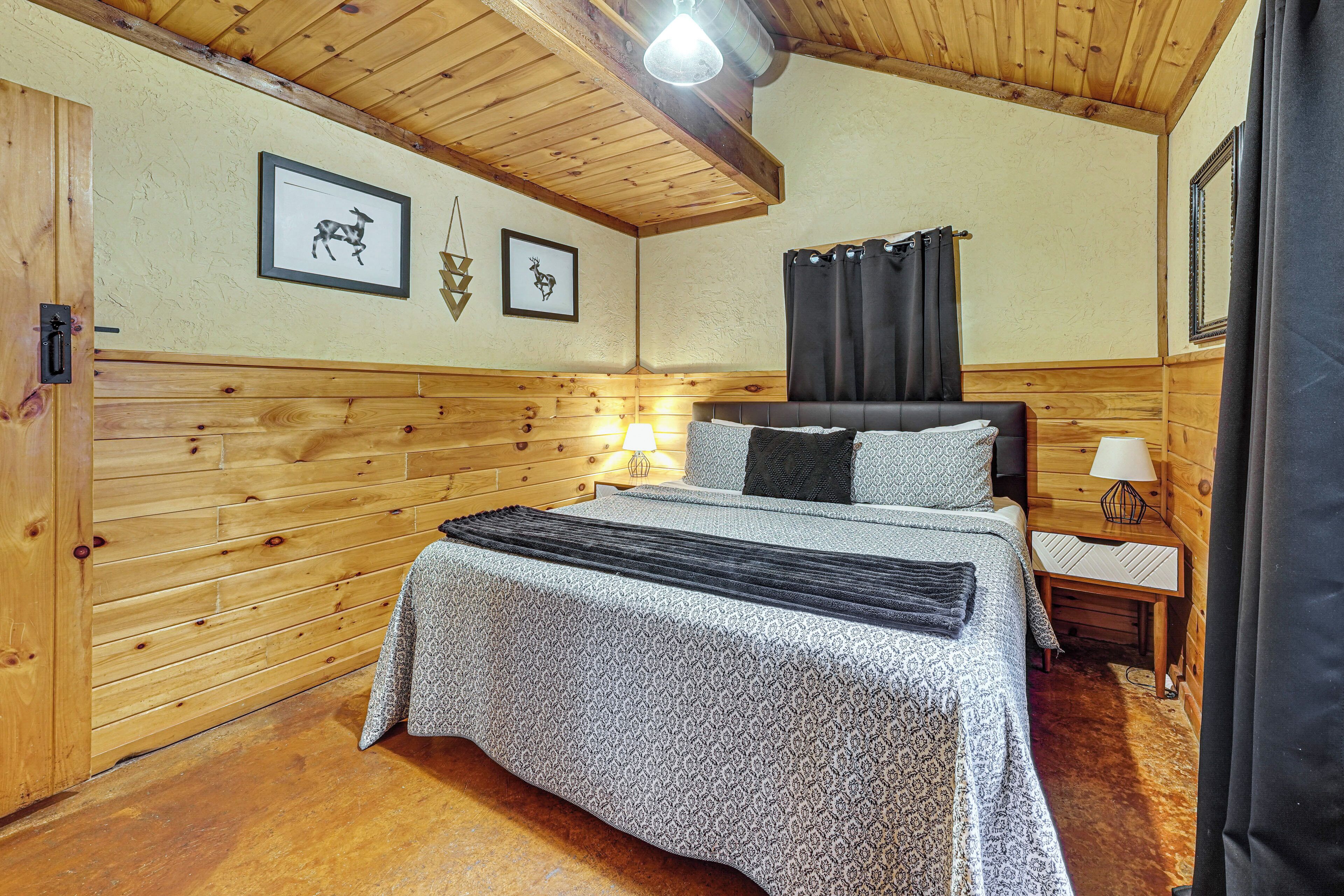 A wooden-paneled bedroom with a bed, a nightstand, and wall-mounted lamps.