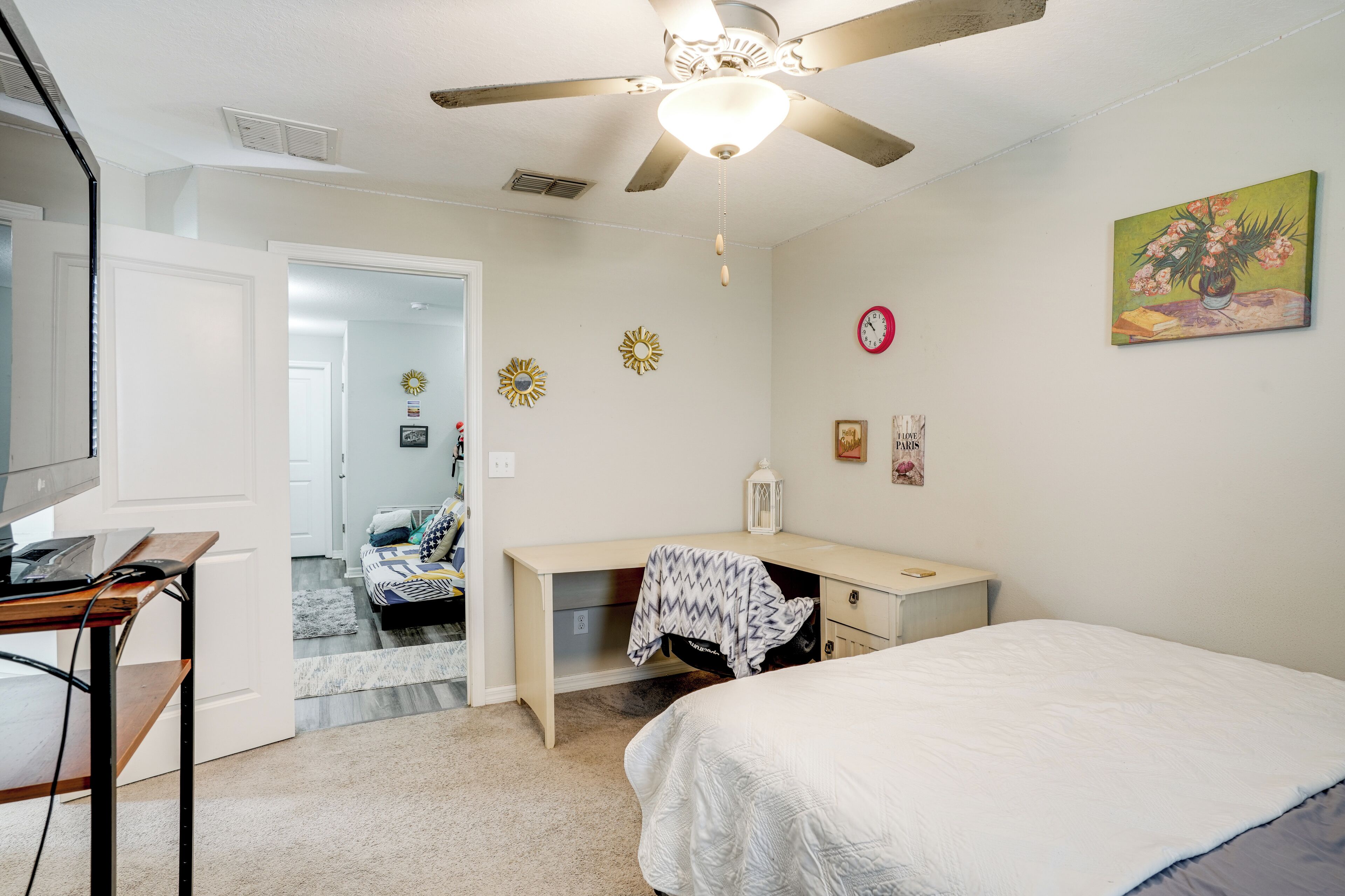 A bedroom with a bed, desk, and ceiling fan.