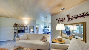 A cozy living room with a sofa, a coffee table, and a lamp. A bookshelf and a mirror are also visible. - Secluded Getaway on ~10 Acres in The Piney Woods! (Winnsboro)