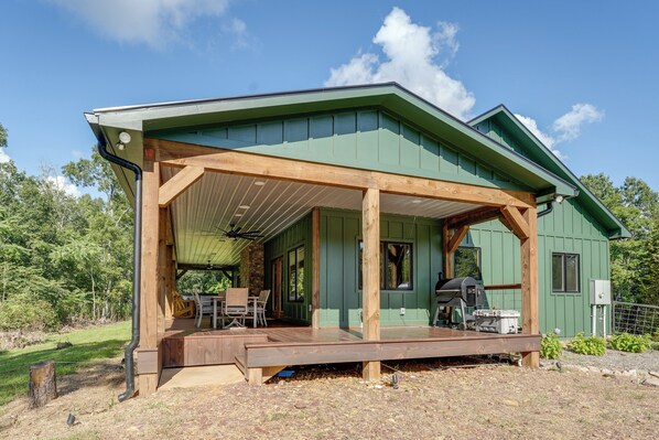 A green house with a wooden deck and a covered patio area. - Hot Tub, Trail Access & 400 Acres on Lavender Mtn! (Rome)