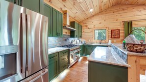 A modern kitchen with green cabinets, stainless steel appliances, and a wooden ceiling. - Hot Tub, Trail Access & 400 Acres on Lavender Mtn! (Rome)