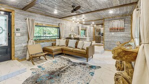 A spacious living area with a large sectional sofa, a wooden coffee table, and a rustic rug. - Hike, Fish & Unwind: Cabin w/ Yard in Broken Bow! (Broken Bow)