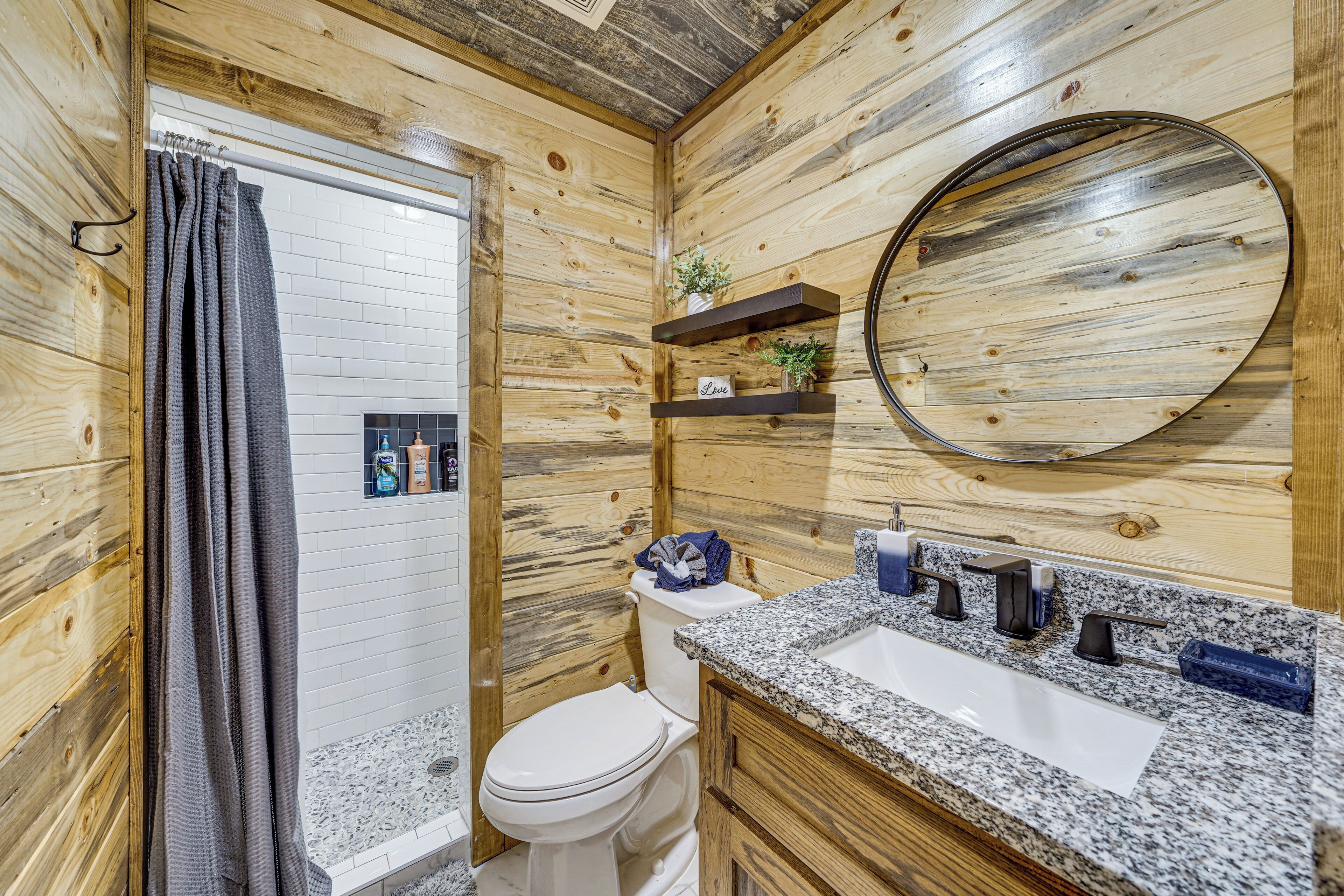 Een badkamer met houten wanden, een wit toilet, een granieten wastafel en een spiegel.