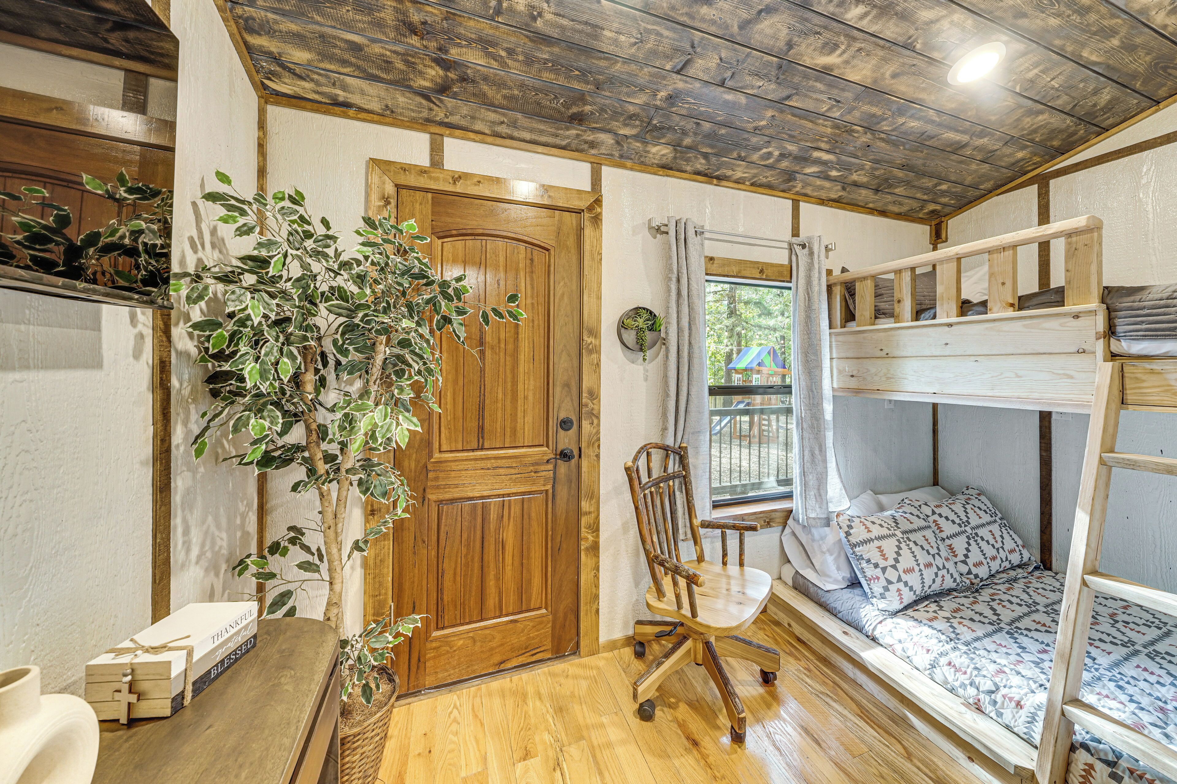 A cozy room with a wooden door, a plant, a chair, and a bunk bed.