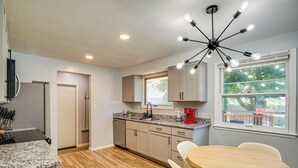 A modern kitchen with granite countertops, a built-in dishwasher, and a dining area with a wooden table and chairs.