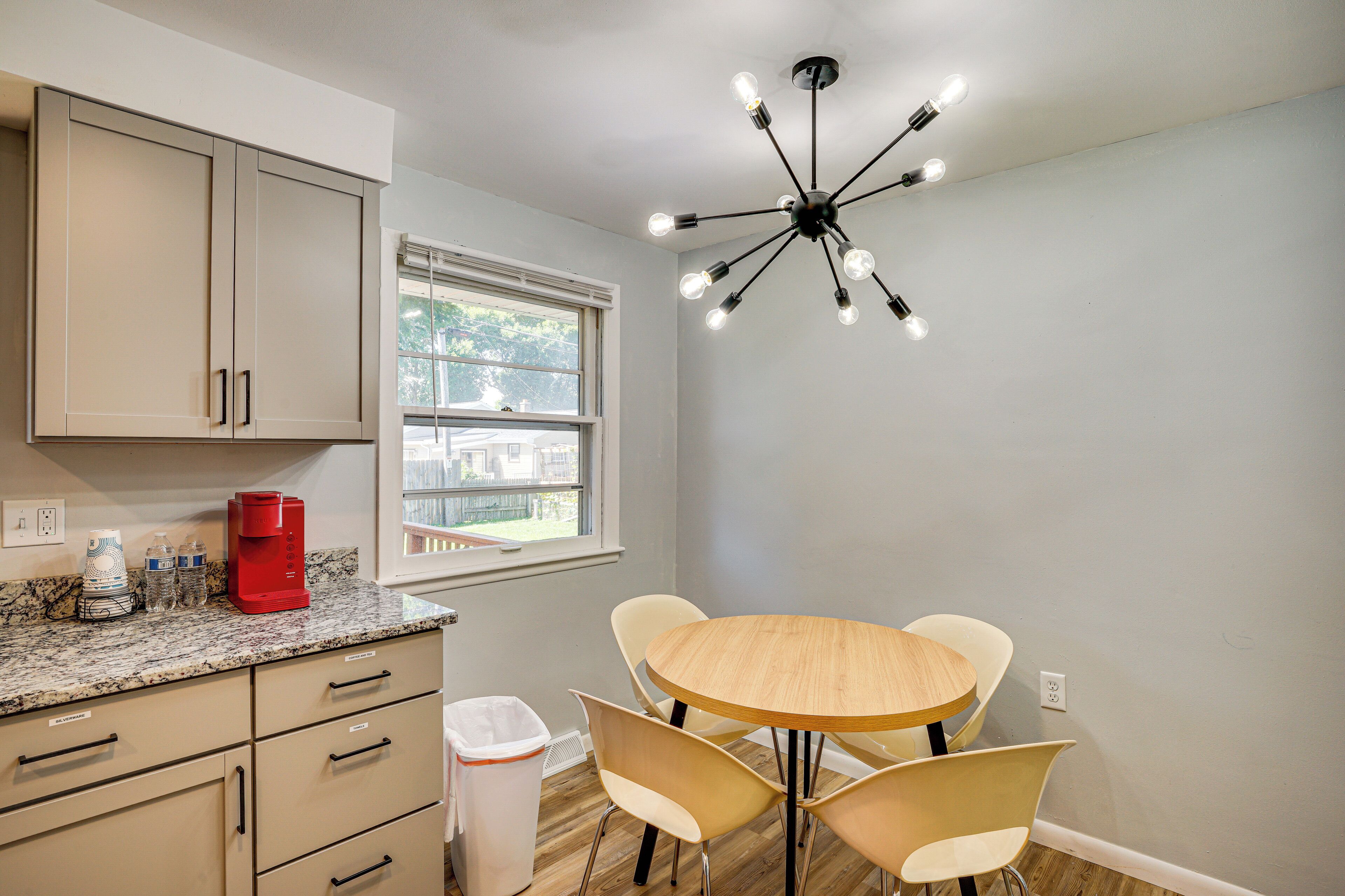 A kitchen with a granite countertop, a coffee maker, and a trash can.