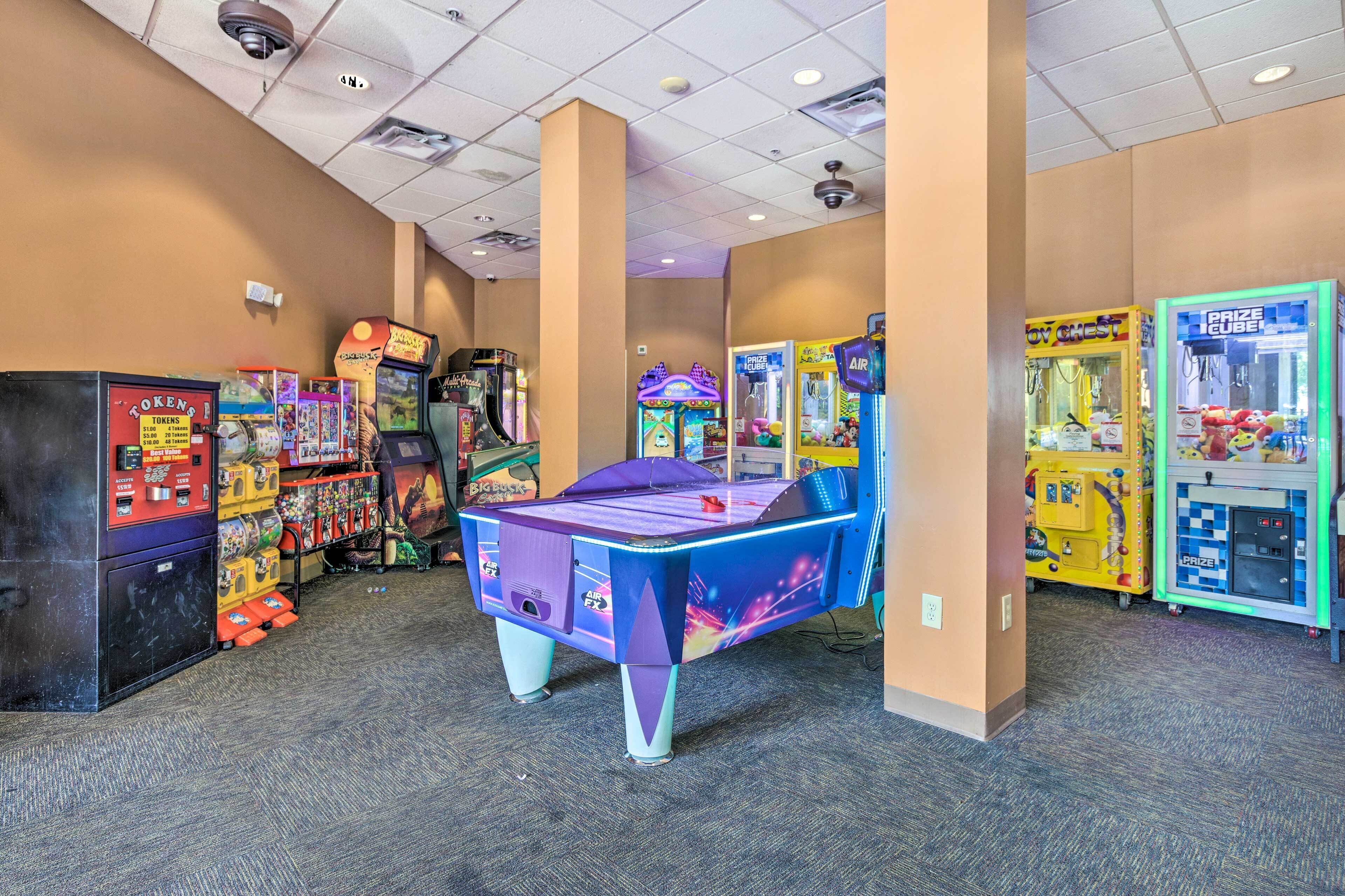 A room with arcade games, a pool table, and vending machines.