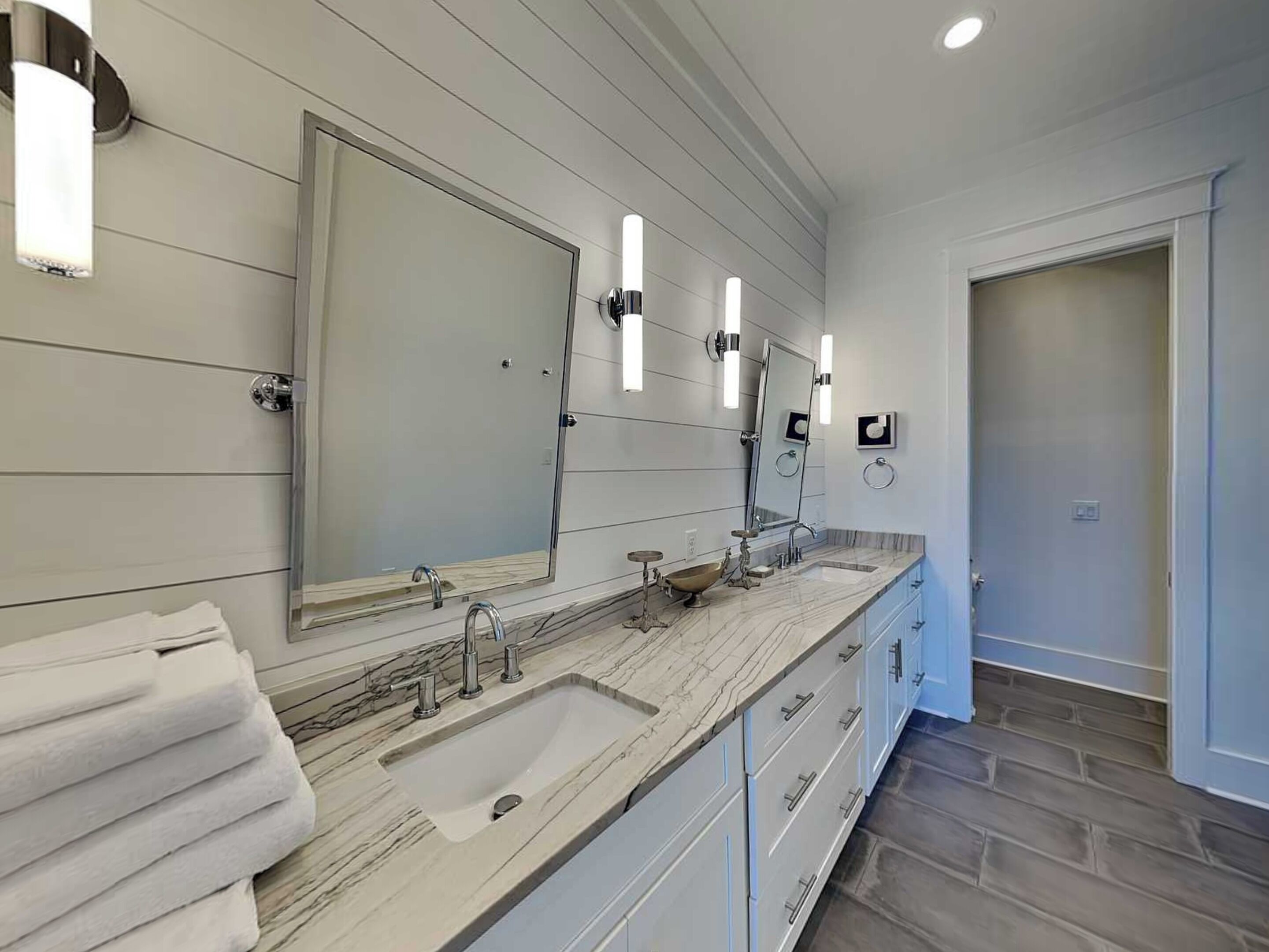 A modern bathroom with a large vanity, double sinks, and a large mirror.