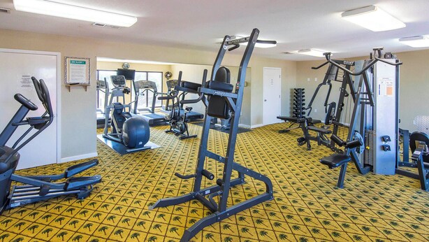 A gym with various exercise equipment, a patterned floor, and a door with a notice.