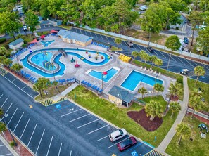Vue aérienne d’un hôtel doté d’une piscine, de plusieurs parkings et entouré de verdure.