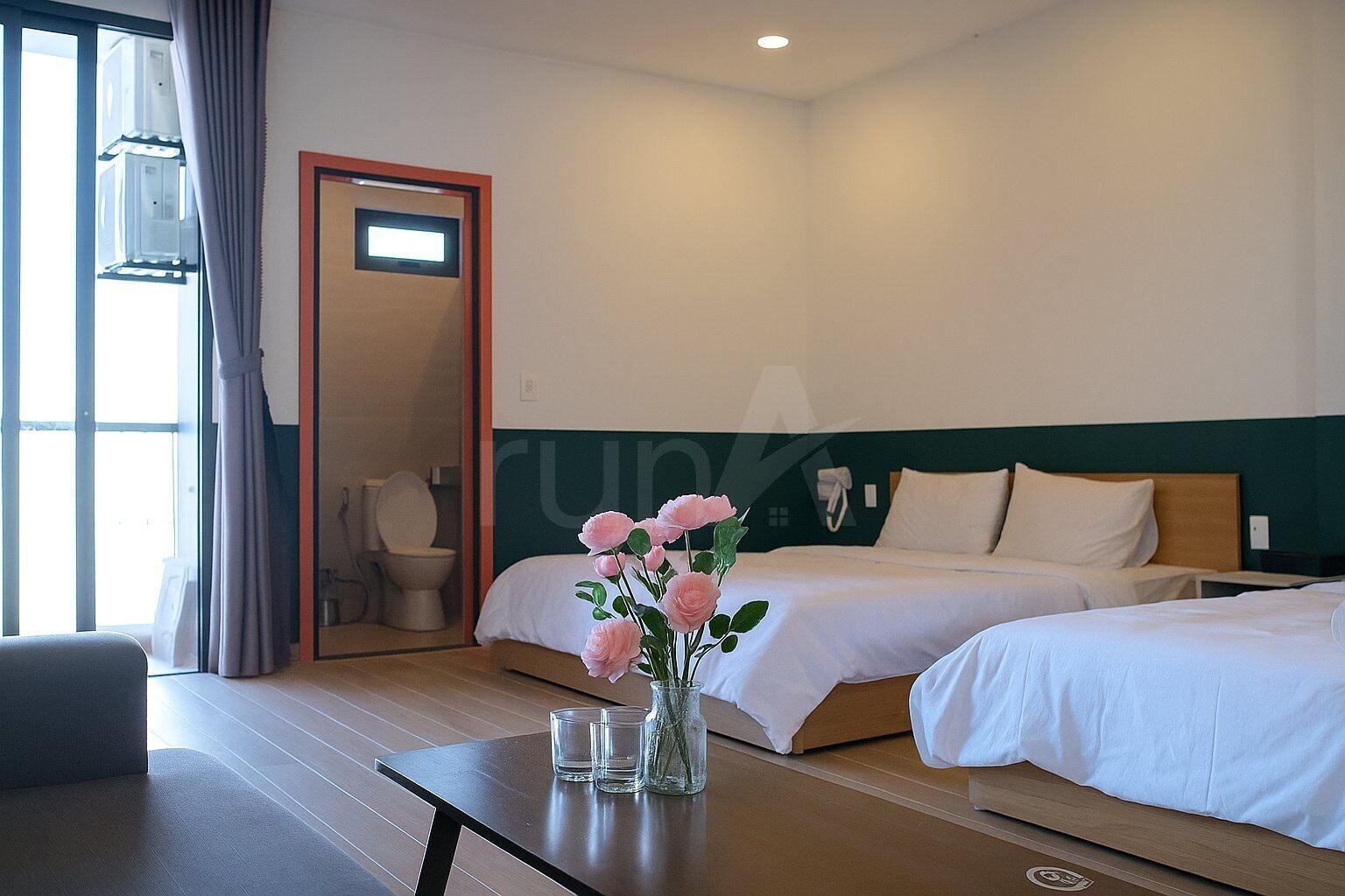 Een hotelkamer met twee bedden, een badkamer en een tafel met een bloevas.