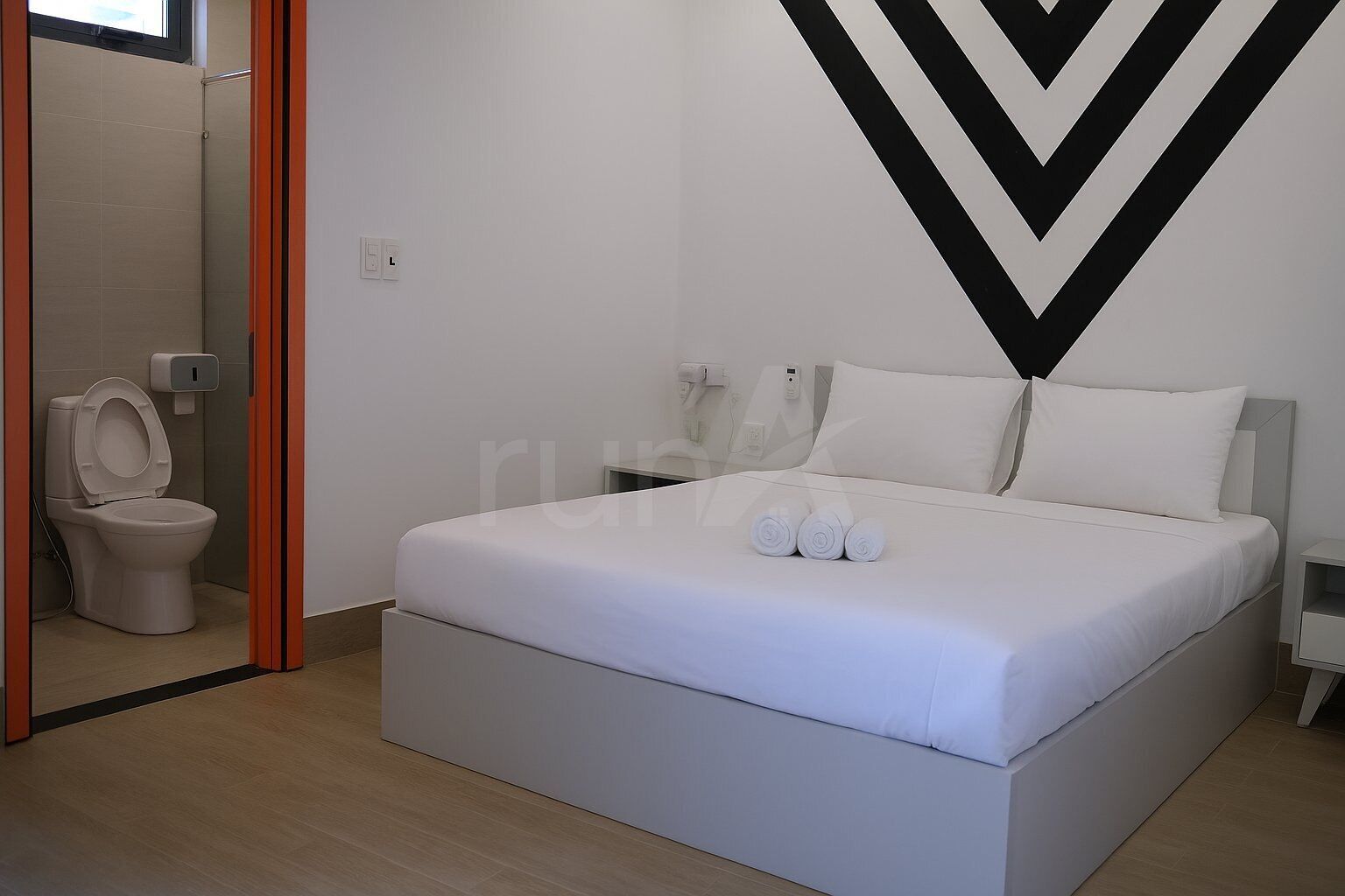 A modern hotel room with a large bed, a toilet, and a mirror.