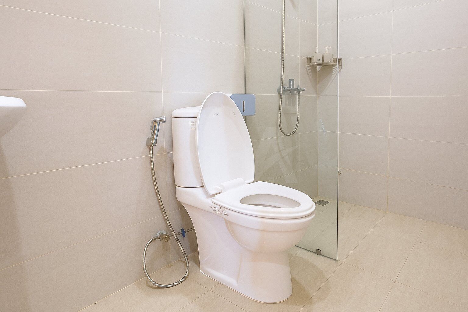 A bathroom with a white toilet, a glass shower enclosure, and a tiled floor.