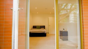 A bedroom with a bed, a dresser, and a window with a view of trees. - Stylish 3BR | 3 Min to Southfields Station (Greater London)