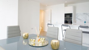 A modern dining area with a glass table, four chairs, and a decorative tray with candles. - Stylish 3BR | 3 Min to Southfields Station (Greater London)