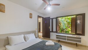 A bedroom with a bed, a ceiling fan, a window with blinds, and a small shelf. - House w/ 3 Suites 400m From Mucuge Beach Mcg0006 (Porto Seguro)