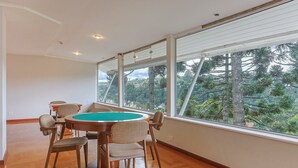 A spacious room with a pool table, large windows, and a view of trees. - Apart w Beautiful View in Campos do Jordao Lvr0003 (Campos do Jordão)