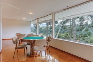 A spacious room with a pool table, large windows, and a view of trees. - Apart w Beautiful View in Campos do Jordao Lvr0003 (Campos do Jordão)