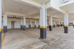 Un estacionamiento con varios niveles, pisos de concreto y pilares con franjas amarillas y negras.