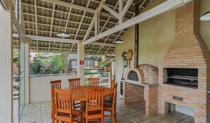 Un patio al aire libre con un horno de ladrillo y una mesa con sillas.