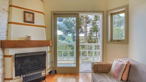 A living room with a fireplace, a sofa, and a large sliding glass door leading to a balcony with a view of trees and a mountain. - Apart w Beautiful View in Campos do Jordao Lvr0003 (Campos do Jordão)