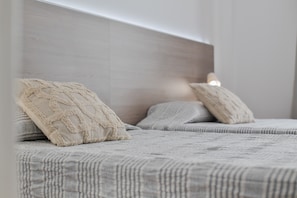 Une chambre à coucher avec une tête de lit, deux oreillers et une couvre-lit à rayures.