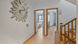 Un pasillo con un espejo de diseño radiante, puertas de madera y una escalera.
