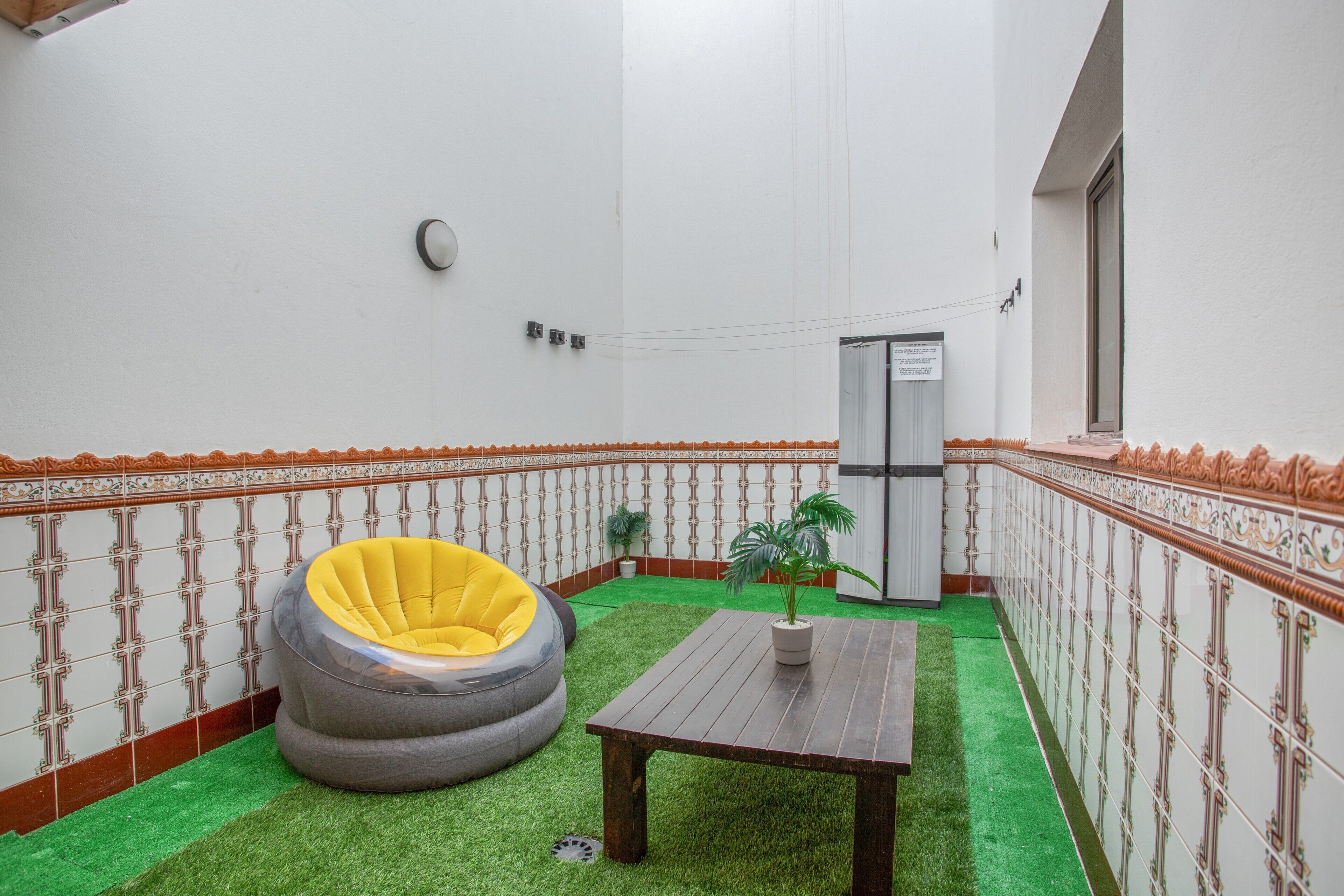 Ein Zimmer mit einem grünen Kunstturfteppich, einem Holztisch und einem gelben Sitzsack.