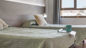 A hotel room with two beds, a window, and a lamp. - 'Corralejo Ian's Dream' with Shared Terrace and Wi-Fi (Corralejo)