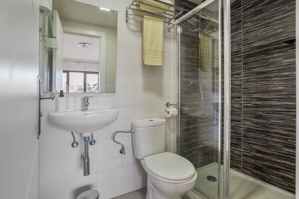 A bathroom with a sink, toilet, and glass shower enclosure.