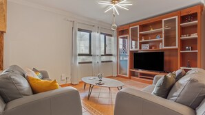 A living room with a sofa, a coffee table, a TV, and a bookshelf.