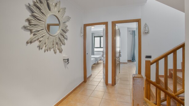 A hallway with a sunburst mirror, wooden doors, and a staircase.